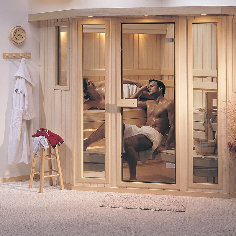 Two people relaxing inside a wooden sauna. Towel rack and robe hang outside. Warm lighting and cozy atmosphere. Wall clock shows time.